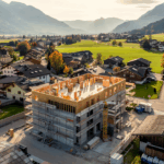 Baustelle eines modernen Wohnkomplexes in Kärnten, eingerahmt von Bergen und städtischer Architektur.