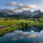 Drohnenaufnahmen Kärnten – sanfte Hügellandschaft mit blauem Bergsee und Bergpanorama.