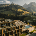 Luxuriöses Hotel in Kärnten mit Panoramablick auf grüne Almen und beeindruckende Berggipfel bei Abendsonne.