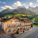 Historischer Gasthof Edelweiss in Kärnten, umgeben von malerischen Berglandschaften und grünen Almwiesen bei Sonnenaufgang.