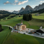 Historisches Berghotel in Kärnten, umgeben von weitläufigen Almwiesen und majestätischen Gipfeln im Abendlicht.