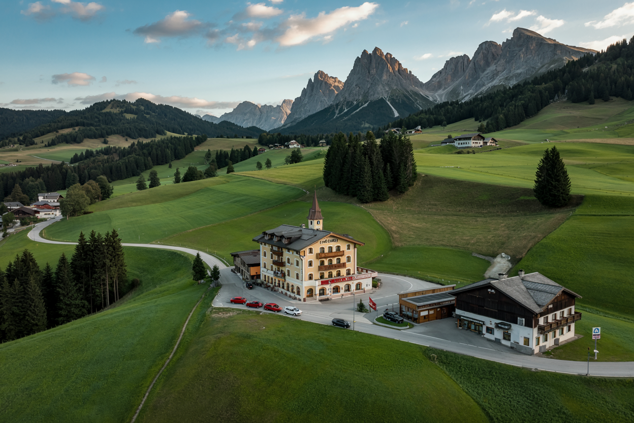 Historisches Berghotel in Kärnten, umgeben von weitläufigen Almwiesen und majestätischen Gipfeln im Abendlicht.